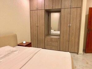 A bedroom with a bed, a nightstand, a wardrobe, and a mirror. - Perfect 2-bedroom apartment in Entebbe for a relaxing stay (Entebbe)