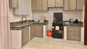 Una cucina compatta con mobili in legno, un fornello a gas, una macchina da caffè e un tostapane.
