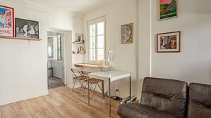 Een woonkamer met een bruine leren bank, een eettafel met stoelen en kunstwerken aan de muren.