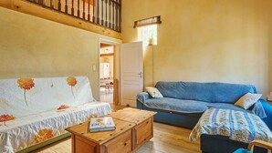 Amplia sala de estar con una mesa de centro de madera, un sofá azul, un sofá blanco con estampado floral y un mueble de madera.