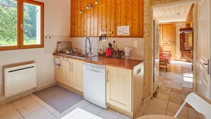 Una cocina compacta con armarios de madera, lavavajillas, pileta y ventana.