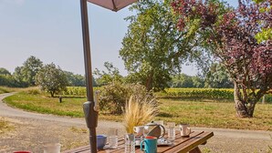 Una mesa de picnic al aire libre con varios objetos, como un hervidor, tazas y vasos.