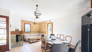 Un salon chaleureux avec une cheminée, une table à manger dressée pour quatre personnes et un canapé.