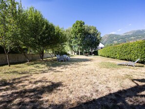 A grassy outdoor area with a table and chairs, surrounded by trees and a hedge. - Large house, pets allowed - 10 guests (Vielle-Aure)