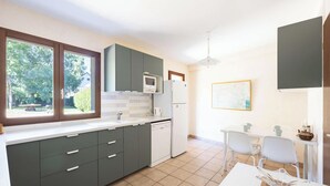 Une cuisine moderne dotée d’une grande fenêtre, d’un coin repas avec une table et des chaises, et d’un réfrigérateur.