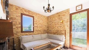 Une pièce avec un mur en briques, un canapé, une table basse en verre, un lustre et une porte donnant sur un balcon.