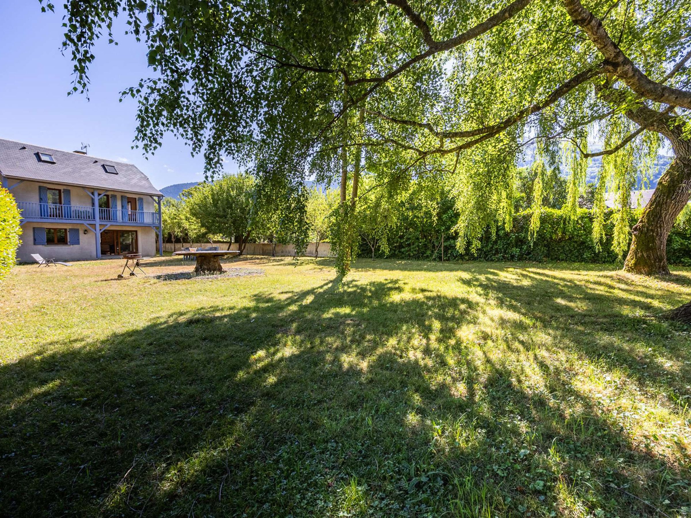 Een huis met een balkon, een gazon en bomen.