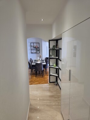 Eine moderne Küche mit Einbaukühlschrank, ein Essbereich mit Tisch und Stühlen sowie ein Flur mit Holzboden.