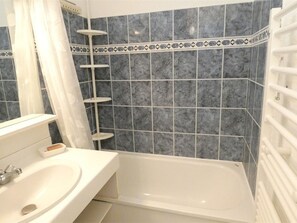 Ein Badezimmer mit einem weißen Waschbecken, einer Badewanne und einer Dusche mit weißem Duschvorhang.
