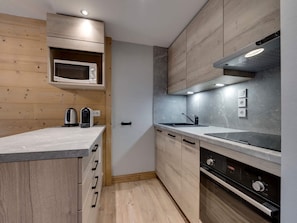 A modern kitchen with wooden cabinets, a microwave, a stove, and a sink. - Comfortable apartment mountain view - 4 guests (Val-d'Isère)