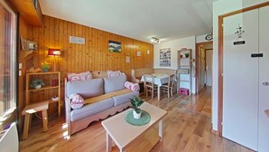 Un accogliente soggiorno con parete in legno, un divano, un tavolino da caffè e un'area pranzo con tavolo e sedie.