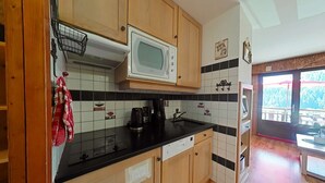 Una cucina con mobili in legno, un forno a microonde, una macchina da caffè e vista su un balcone.