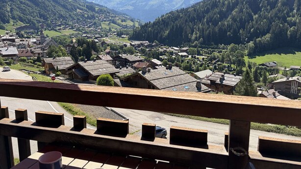 Un borgo montano con case tradizionali, una strada con un segnale di stop e vista sulle montagne circostanti.