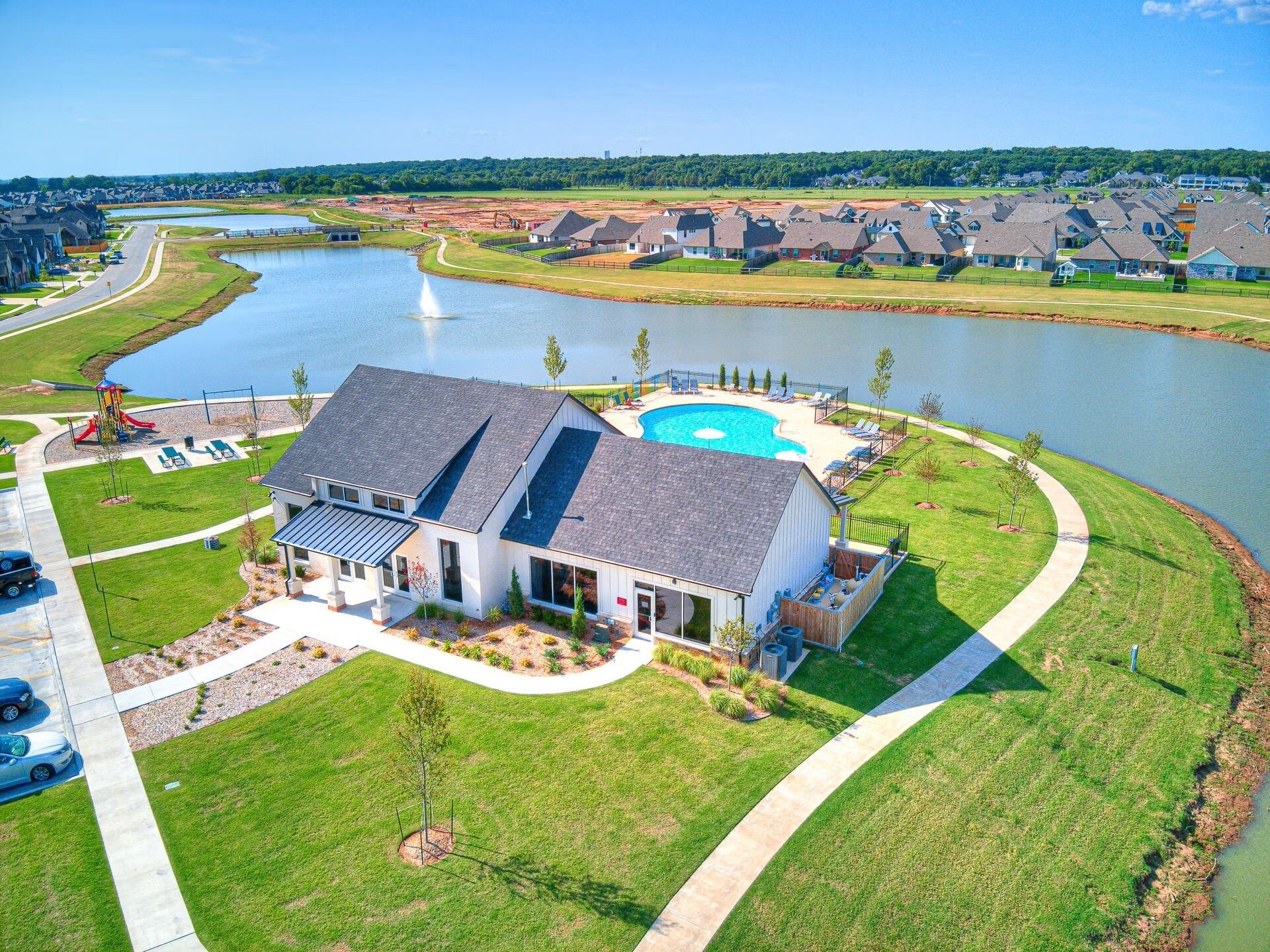 A residential area with a house featuring a large swimming pool, a driveway, and a well-maintained lawn.