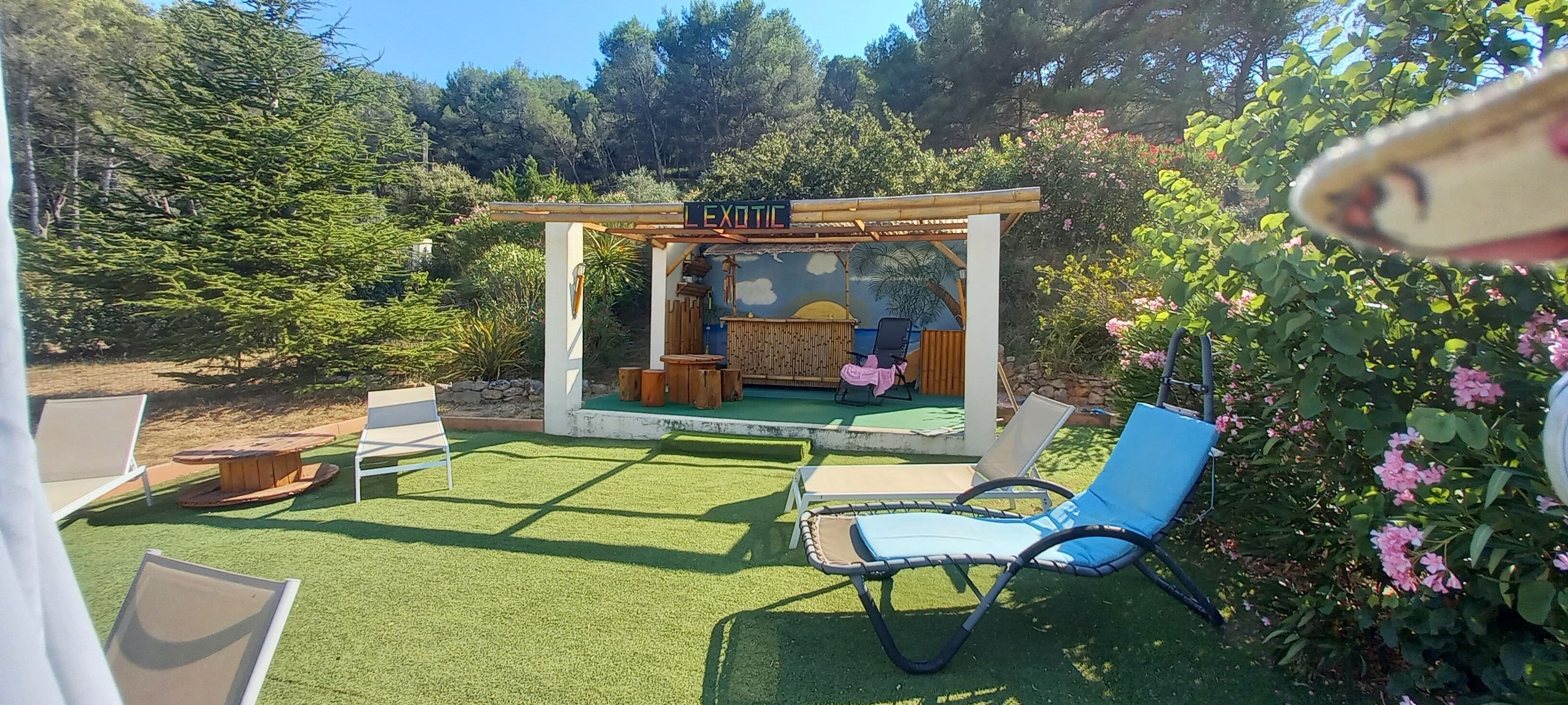 Zona d'estar a l'aire lliure amb una pèrgola, una taula i cadires.