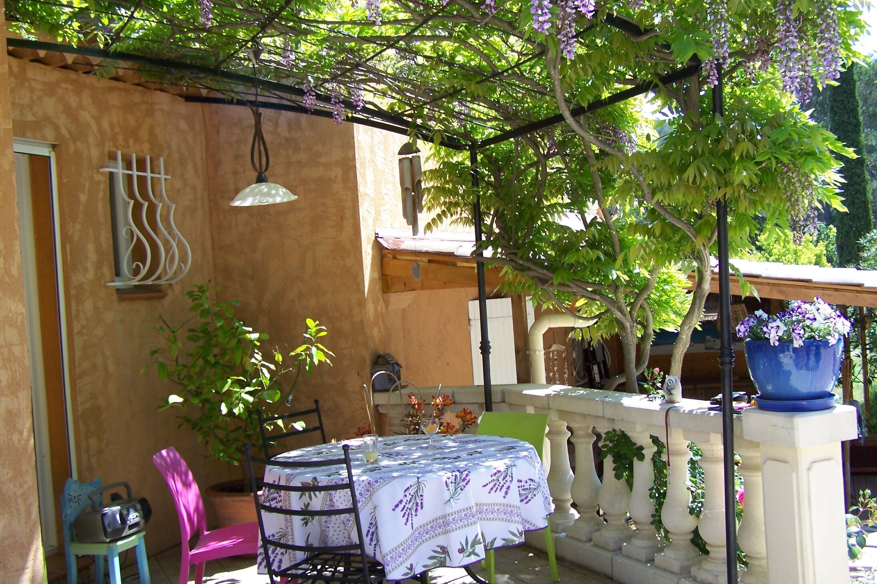 A patio with a table and chairs, a hanging light fixture, and a potted plant.