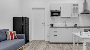 Eine kleine Küche mit weißen Schränken, einem schwarzen Kühlschrank und einem Holzboden.