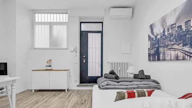 Ein schlicht eingerichteter Raum mit einem Bett, einem Schreibtisch und einer Heizung.