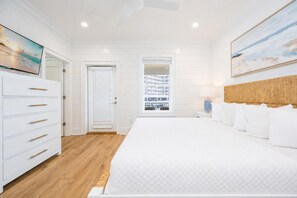 Ein Schlafzimmer mit einem Bett, einem Schminktisch, einem Nachttisch, einer Lampe und einem Gemälde an der Wand.