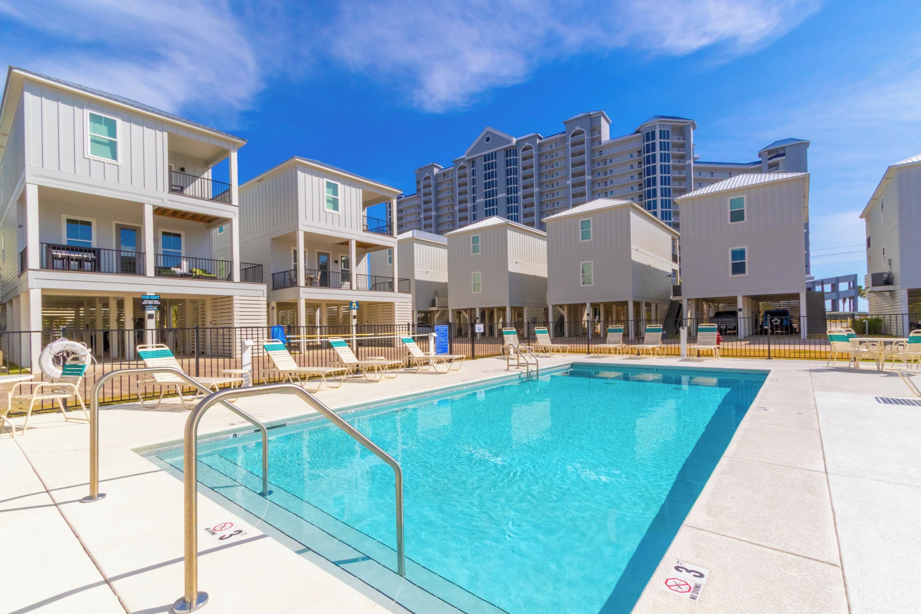 A swimming pool area with lounge chairs and a poolside bar, surrounded by multi-story buildings with balconies.