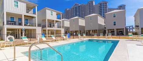 A swimming pool area with lounge chairs and a poolside bar, surrounded by multi-story buildings with balconies.