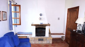A living room with a blue sofa, a fireplace, a wooden cabinet, and a checkered curtain.