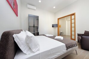 A hotel room with a bed, a seating area, a wardrobe, and a television. - 4BNB - Luxury Chinotto Apartment (Roma)