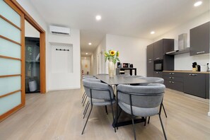 Cocina moderna con gabinetes grises, horno empotrado y comedor con sillas y mesa grises.