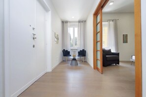A hallway with a dining area, a sofa, and a window with curtains. - 4BNB - Luxury Chinotto Apartment (Roma)