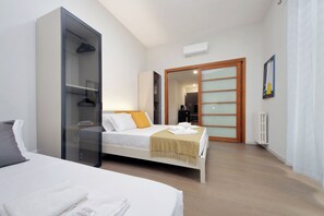 Ein Schlafzimmer mit einem Bett, einem Kleiderschrank, einem Heizkörper und einer Tür zu einem anderen Raum.