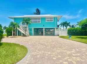 A two-story building with a staircase on the left, a gated entrance, and a paved driveway. - Tropical canal home - private pool, Fort Myers Beach, dock, direct gulf access (Fort Myers Beach)