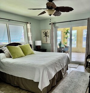 A bedroom with a bed, a ceiling fan, a window with blinds, a lamp, and a door leading to a balcony. - Tropical canal home - private pool, Fort Myers Beach, dock, direct gulf access (Fort Myers Beach)