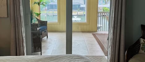 Une chambre d’hôtel avec un lit, une vue sur la piscine et un balcon aménagé avec du mobilier d’extérieur.