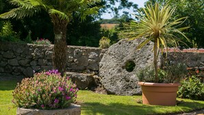 A garden with a stone wall, a tree, and a potted plant. - Penrallt - sleeps 8 guests  in 4 bedrooms (Benllech)