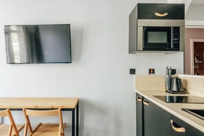 A modern kitchen with a flat-screen TV, a microwave, and a coffee maker. - The Knaresborough by nestor - Earl's Court Apt. (London)
