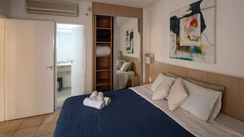 A hotel room with a bed, a wardrobe, a bathroom, and a painting on the wall.