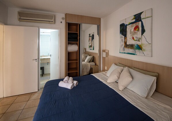 A hotel room with a bed, a wardrobe, a bathroom, and a painting on the wall. - SHB Azul Infinito Sua Janela para o Mar (Santos)