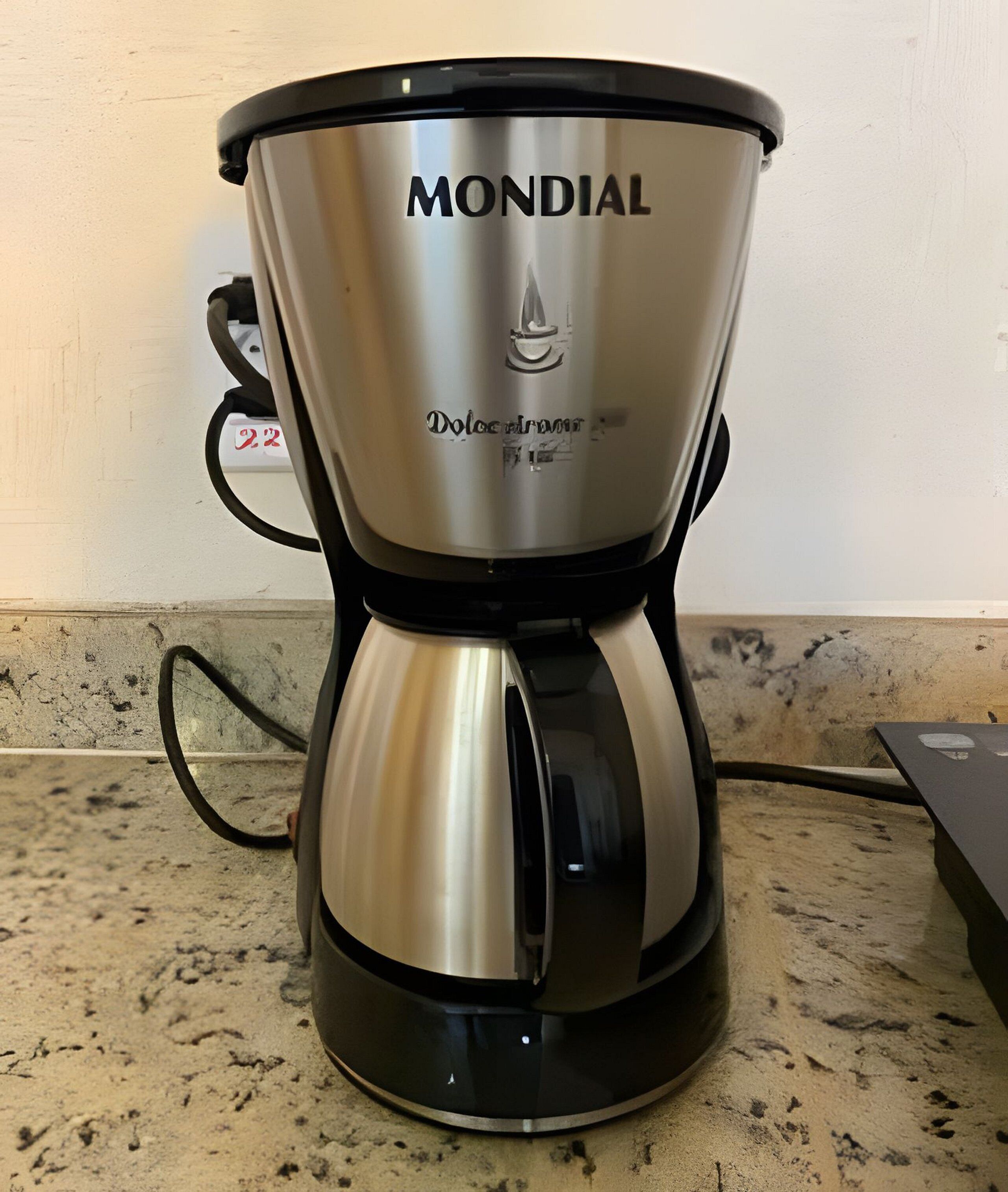 Una cafetera Mondial Dolce Aroma de acero inoxidable sobre una encimera de cocina.