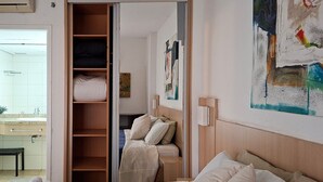 Hotellihuone, jossa on sänky, vaatekaappi, kylpyhuone ja taulu seinällä.