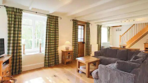 A living room with a sofa, a coffee table, a television, and a staircase leading to another level. - Cornwall Cottage - Sleeps 6 - Garden - Pets (Bodmin)