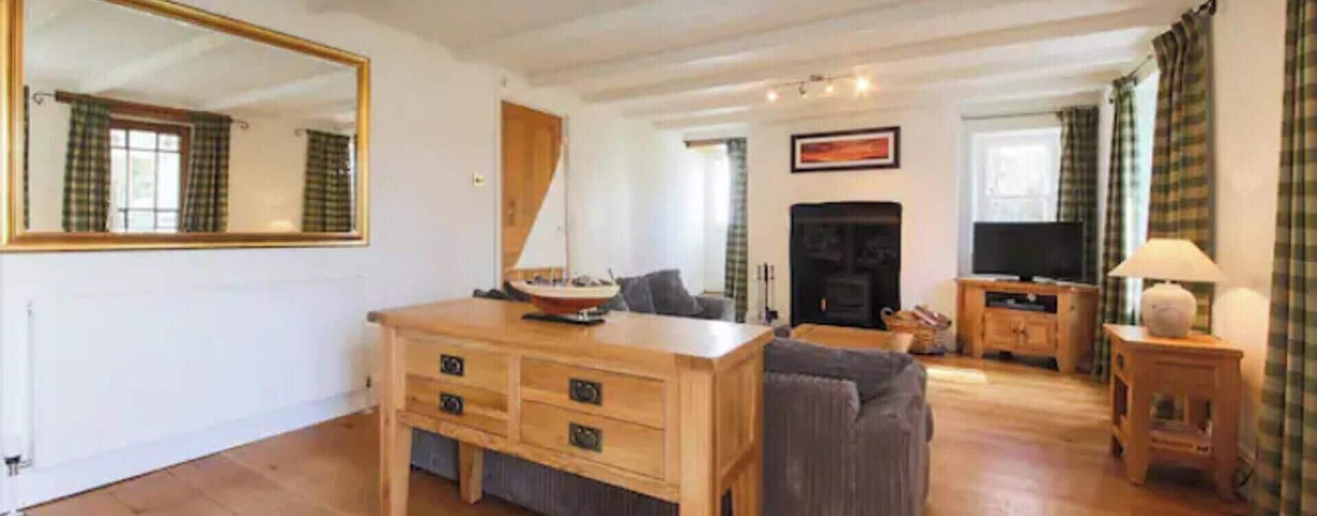 Una sala de estar con una mesa de centro de madera, un sofá, una chimenea y un televisor.