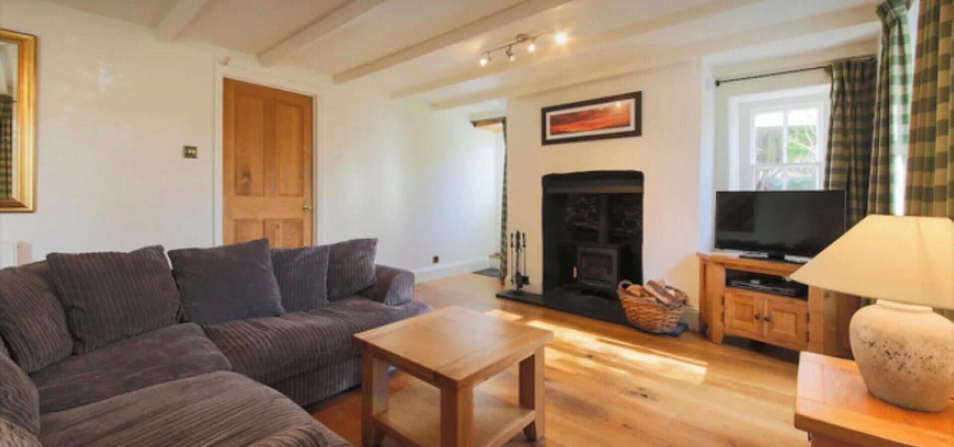 A living room with a sofa, a coffee table, a fireplace, and a television.