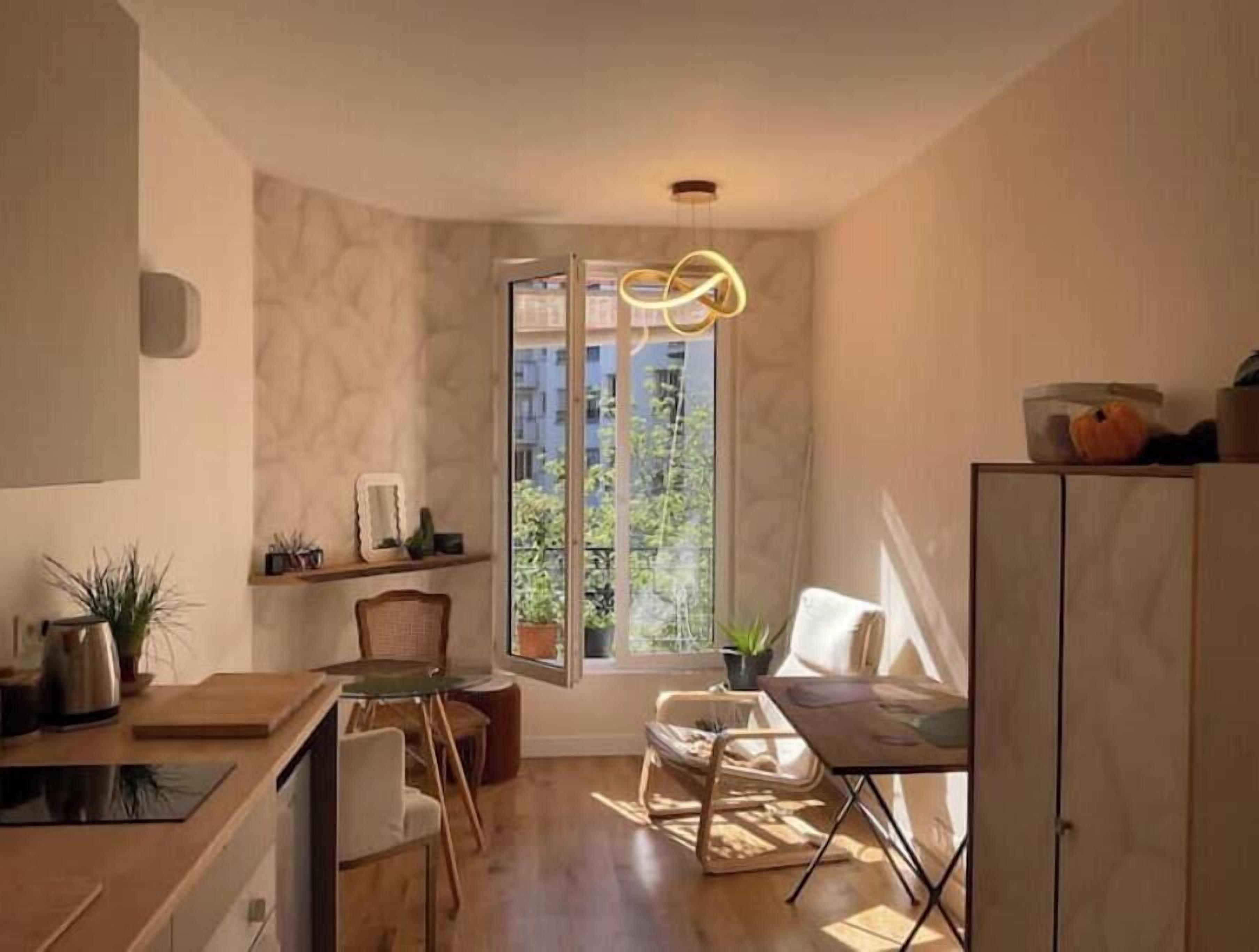 Une cuisine compacte avec un coin repas, une fenêtre offrant une belle vue et un luminaire suspendu moderne.