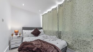 Ein modernes Schlafzimmer mit einem Bett, Nachttischen, einer Lampe und einem großen Spiegel.