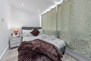 Ein modernes Schlafzimmer mit einem Bett, Nachttischen, einer Lampe und einem großen Spiegel.