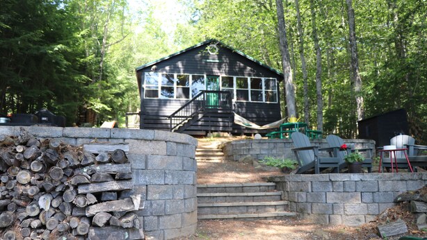 A cabin with a staircase leading to a porch, surrounded by trees.