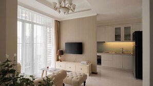 Una sala de estar moderna con televisor, sofá y comedor, con una cocina al fondo.