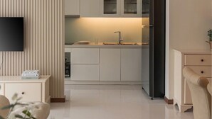 Una cocina moderna con televisor de pantalla plana, refrigerador y comedor con una silla.
