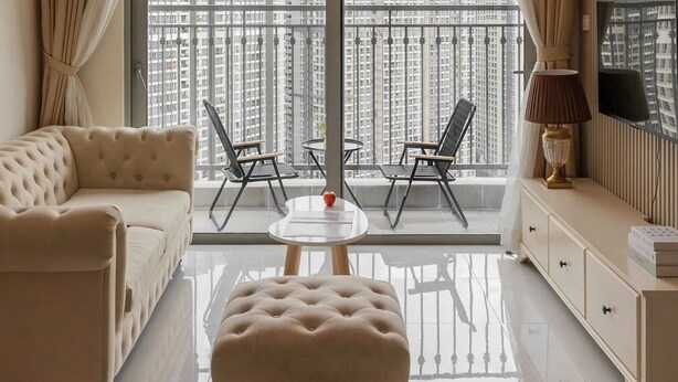 Una sala de estar moderna con sofá, reposapiés y un balcón con sillas.