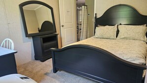 A bedroom with a bed, a dresser, a mirror, and a door leading to a bathroom. - Secluded Vermont Escape – Mins to River, Trails, & Foliage (Sharon)